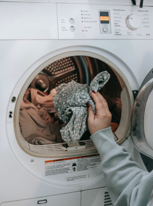 person loading clother into a dryer